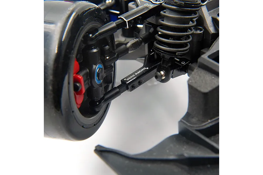 Close-up of a black Yeah Racing aluminium front lower suspension arm installed on an RC car chassis.