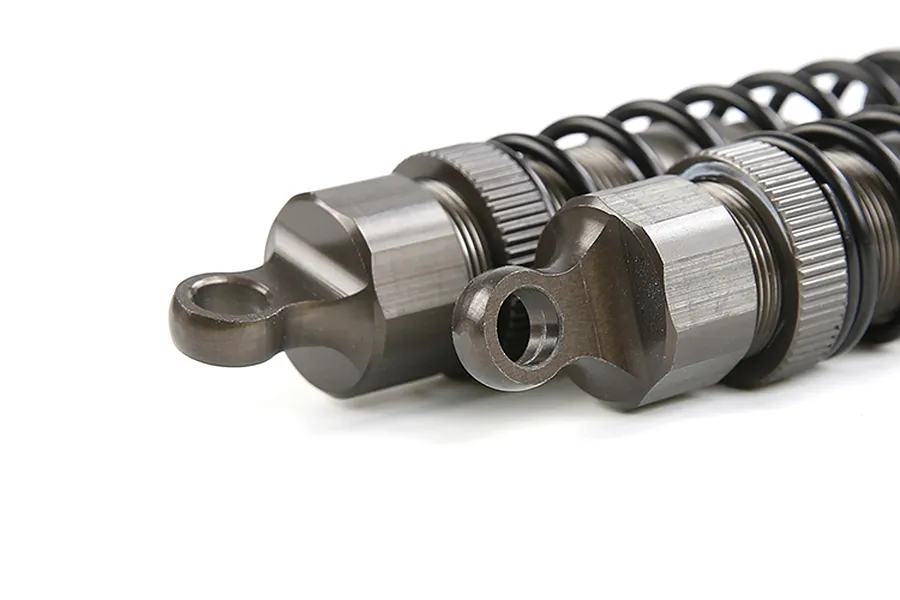 A close-up view of two gunmetal-coloured adjustable RC shock absorbers showing the top mounting points and threaded bodies.