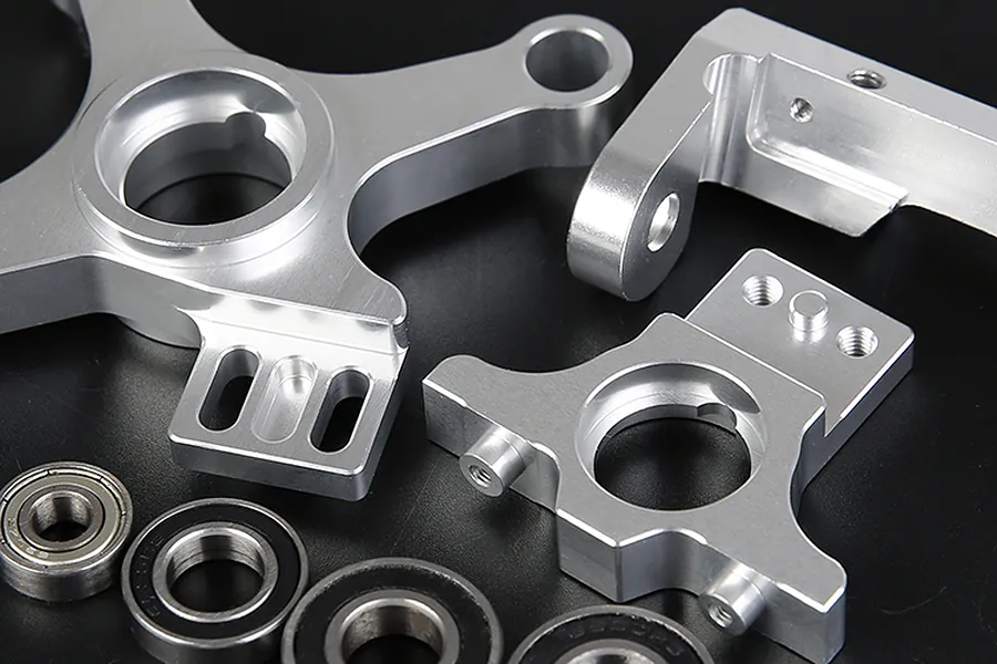 A Rovan complete clutch mount set featuring machined silver aluminum parts and several ball bearings on a black background.