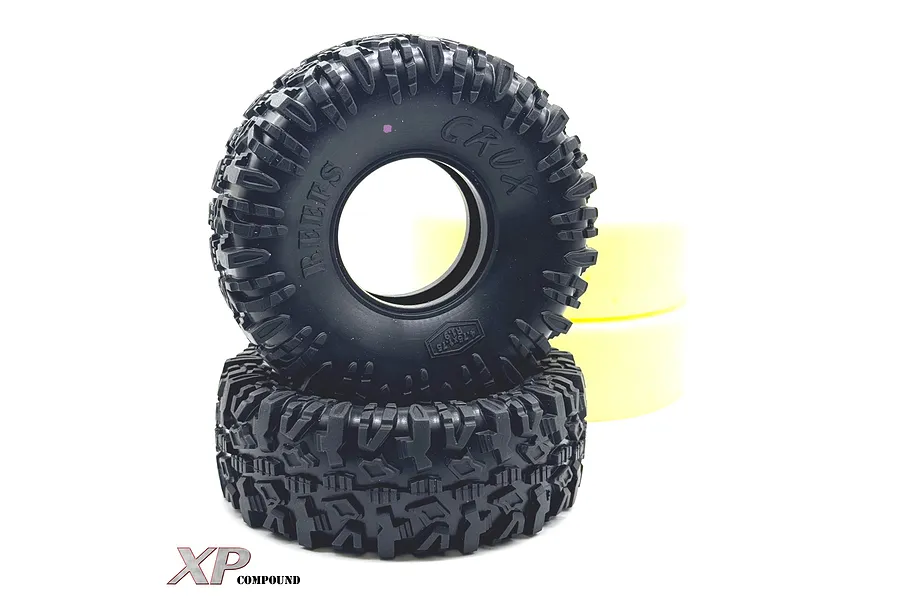 Two black Reefs RC 1.9 inch Crux crawler tyres stacked vertically with yellow foam inserts visible behind them against a white background.