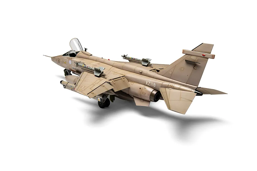 A high-angle studio shot of a 1/48 scale SEPECAT Jaguar GR.1 model aircraft, painted in desert camouflage, on a white background.