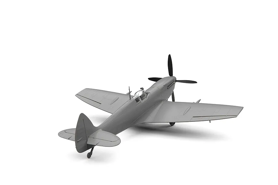 An unpainted grey plastic model of a Supermarine Spitfire Mk.IXe fighter aircraft, viewed from the rear three-quarter angle against a white background.