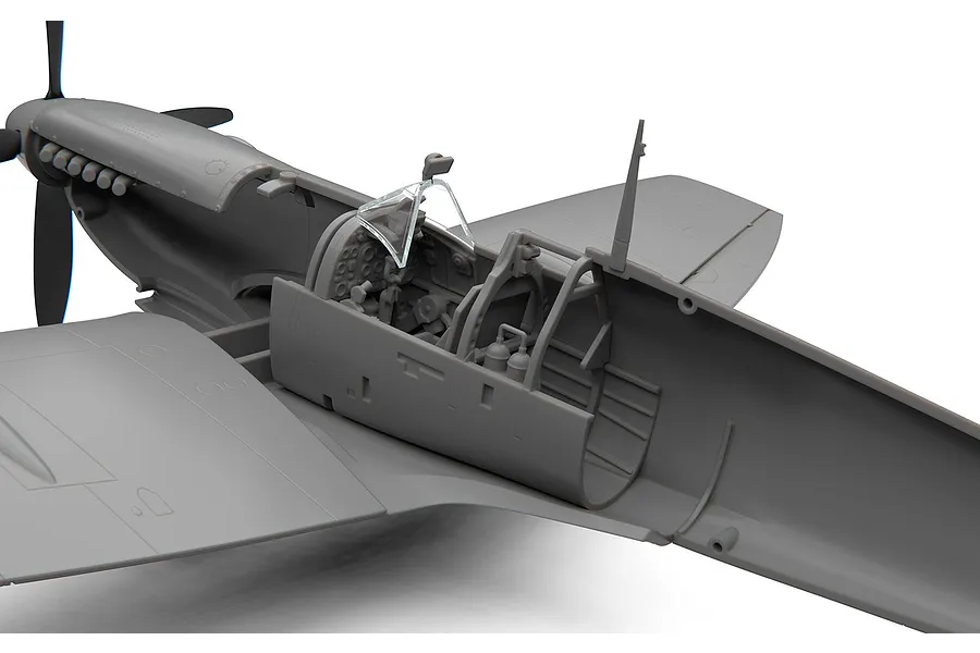 Close-up of an unassembled grey plastic model Spitfire cockpit showing interior detail and clear canopy parts.