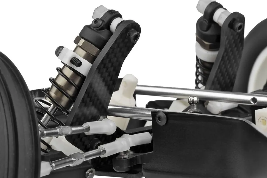 Close-up of the front suspension assembly on a Team Associated RC10 buggy, showing carbon fiber shock towers, coil-over shocks, and steering linkages.