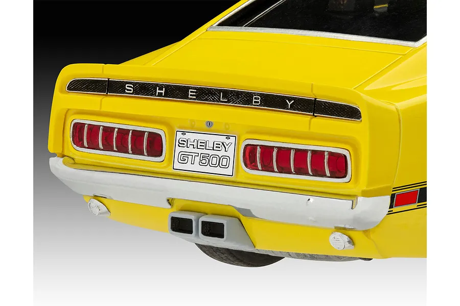 Close-up of the rear of a yellow 1970 Shelby Mustang GT500 model car, showing the taillights, license plate, and central exhaust pipes.