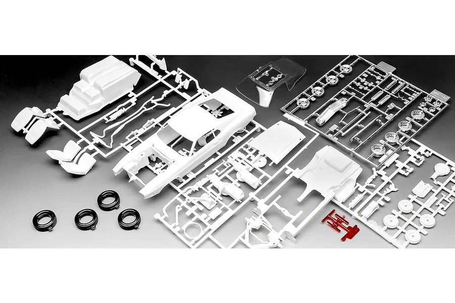 Unassembled plastic model car kit parts including white body shell, chrome wheels, and black rubber tires on a dark background.