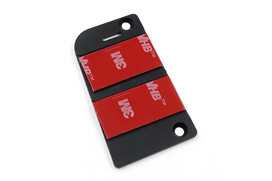 A black aluminium servo mount from Yeah Racing with two red 3M VHB adhesive pads attached to the surface.
