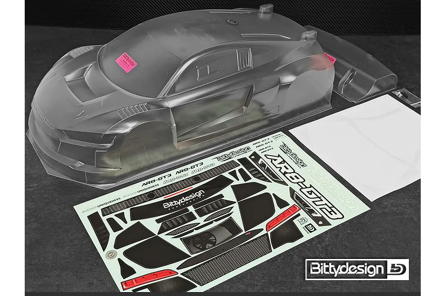 Unpainted clear polycarbonate RC car body shell for 1/8 scale GT3, including a rear wing, decal sheet, and window masks on a dark surface.