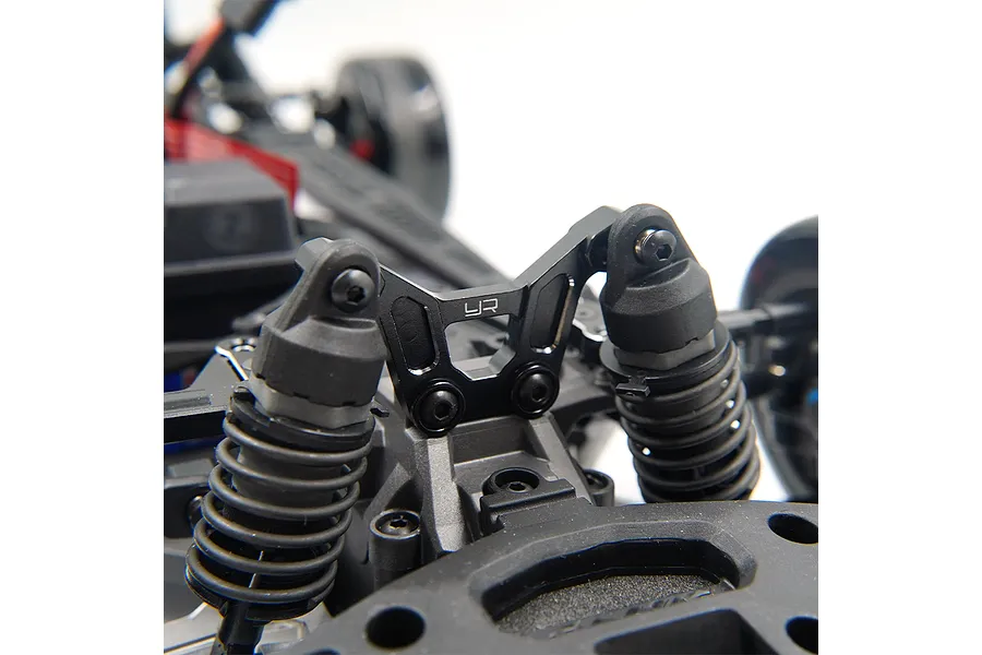 A black aluminium Yeah Racing front shock tower installed on an RC car chassis, featuring the YR logo engraved on the center.