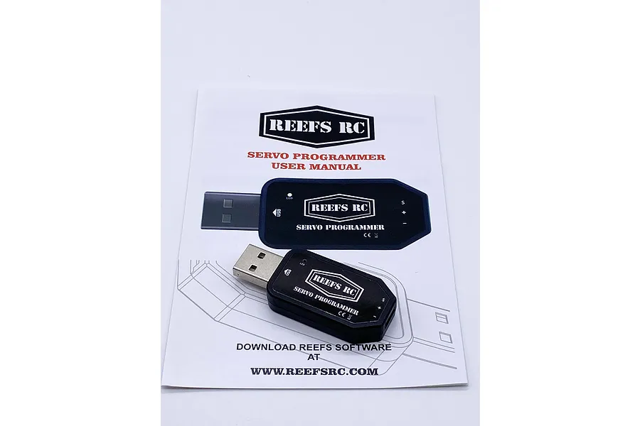 A Reefs RC USB servo programmer device resting on top of its printed user manual.