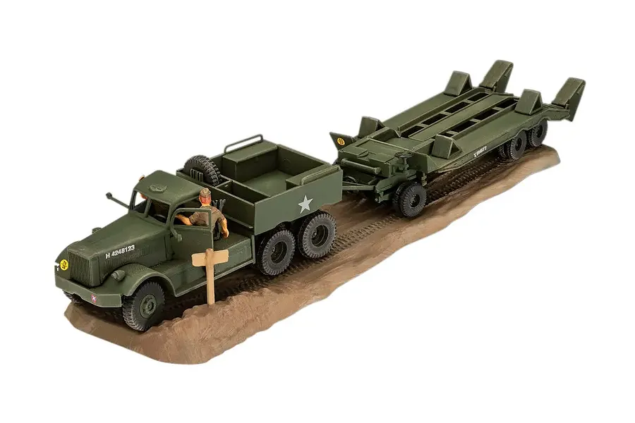 A 1/72 scale plastic model of an M19 tank transporter truck and trailer, painted in olive drab, displayed on a textured brown base.