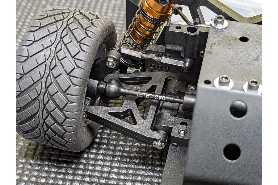 Close-up of an MIP CVD driveshaft installed on an RC car suspension assembly, showing the black metal shaft with MIP branding and a rubber tire.