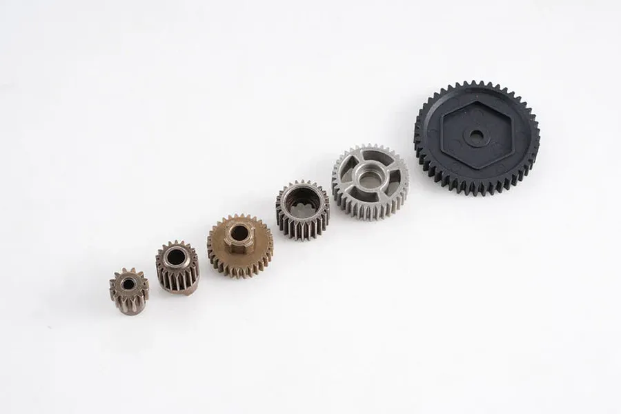 A set of five various sized RC transmission gears including metal pinions and a large black plastic spur gear arranged on a white background.