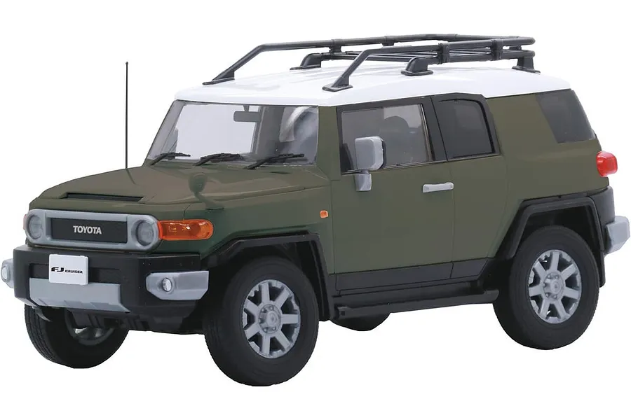 A 1/24 scale plastic model of an olive green and white Toyota FJ Cruiser SUV with a roof rack, shown from a front three-quarter angle.