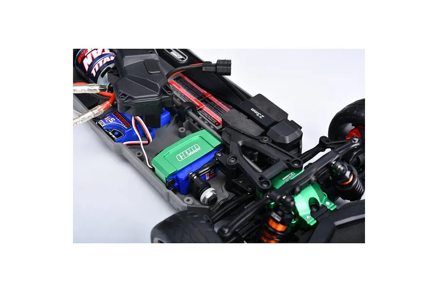 A green GPM Racing aluminium servo mount installed in a Traxxas RC car chassis, showing the servo and surrounding components.