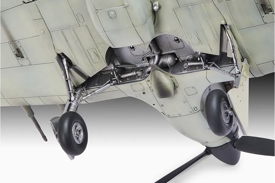 Close-up view of the underside of a plastic model aircraft showing the landing gear, wheel wells, and propeller.