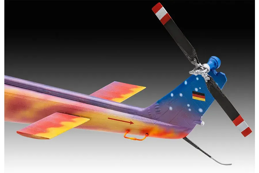 Close-up of the tail section of a model Bell UH-1D helicopter with a custom 'Goodbye Huey' paint scheme featuring flames and a German flag.