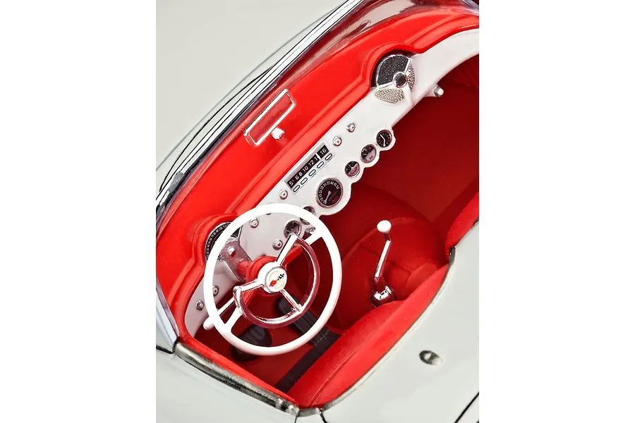 Close-up interior view of a 1/24 scale model 1953 Chevrolet Corvette, showing the white steering wheel, red dashboard, and detailed instrument cluster.