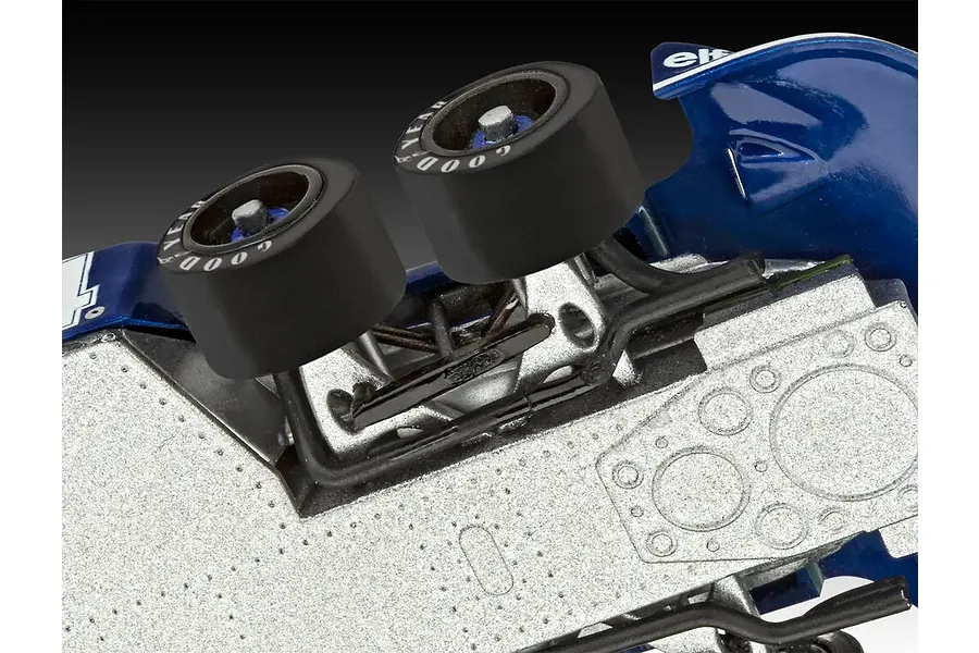Close-up view of the front suspension and dual front wheels of a Tyrrell P34 Formula 1 model car, showing metallic chassis detail.