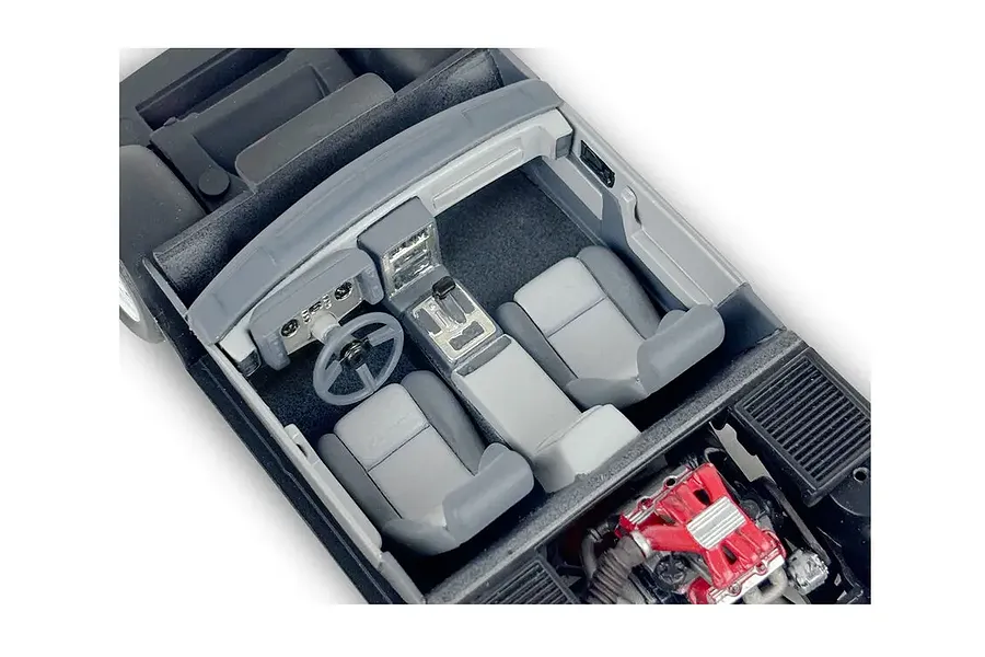 Top-down view of the interior and engine bay of a 1/24 scale model Pontiac Fiero GT, showing grey seats, dashboard, and a red engine block.
