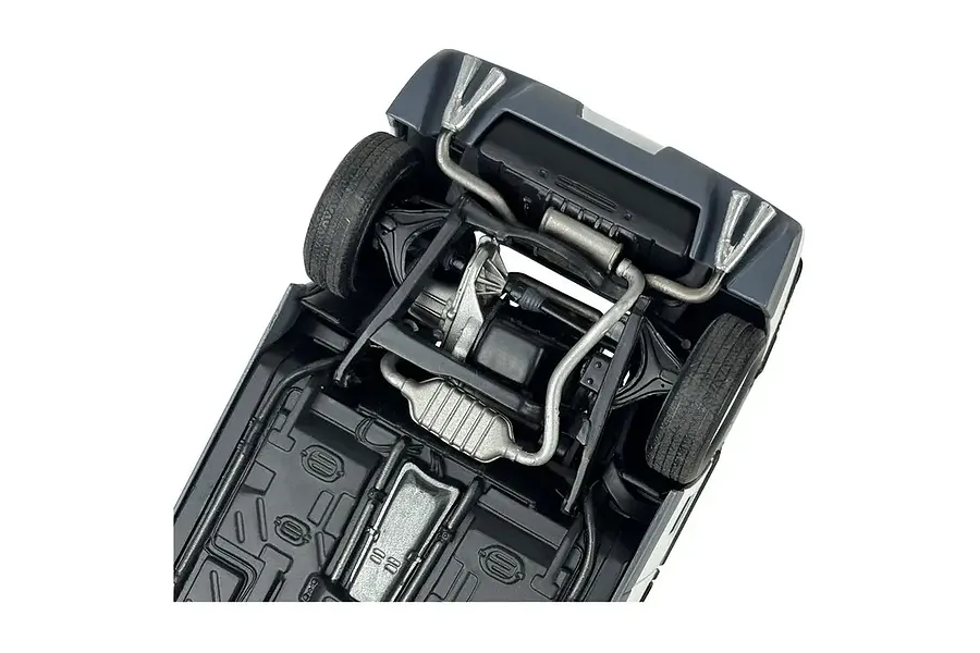 Underside view of a 1/24 scale model Pontiac Fiero GT showing the chassis, exhaust system, and rear suspension details.