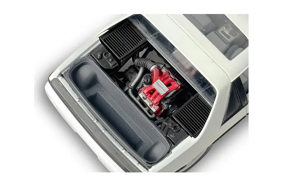 Top-down view of the engine bay of a 1/24 scale model Pontiac Fiero GT, showing the red engine block and surrounding black plastic components.