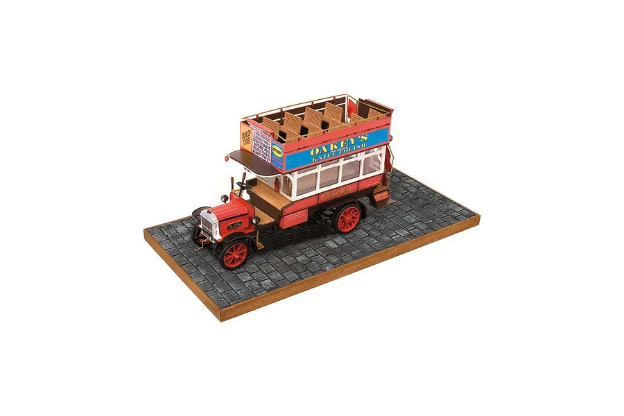 A high-angle studio shot of a completed OcCre 1/24 scale AEC B-Type London bus wooden model kit, displayed on a cobblestone-textured base.