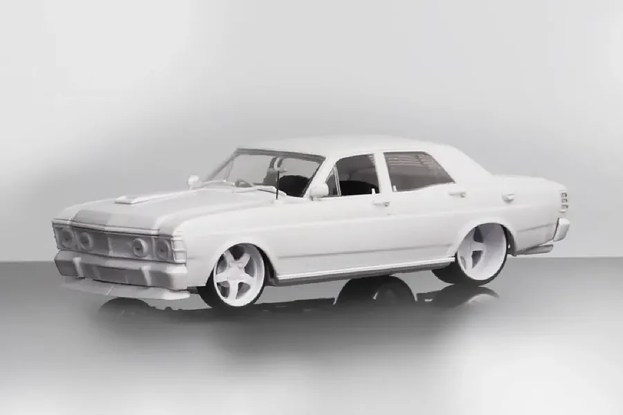 A 1/24 scale unpainted white plastic model of a Ford GTHO XW sedan with custom wheels, shown from a three-quarter front angle.