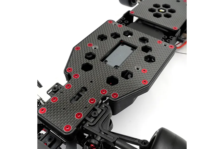 Close-up of a carbon fiber RC car chassis plate with red anodized screws installed on a white background.