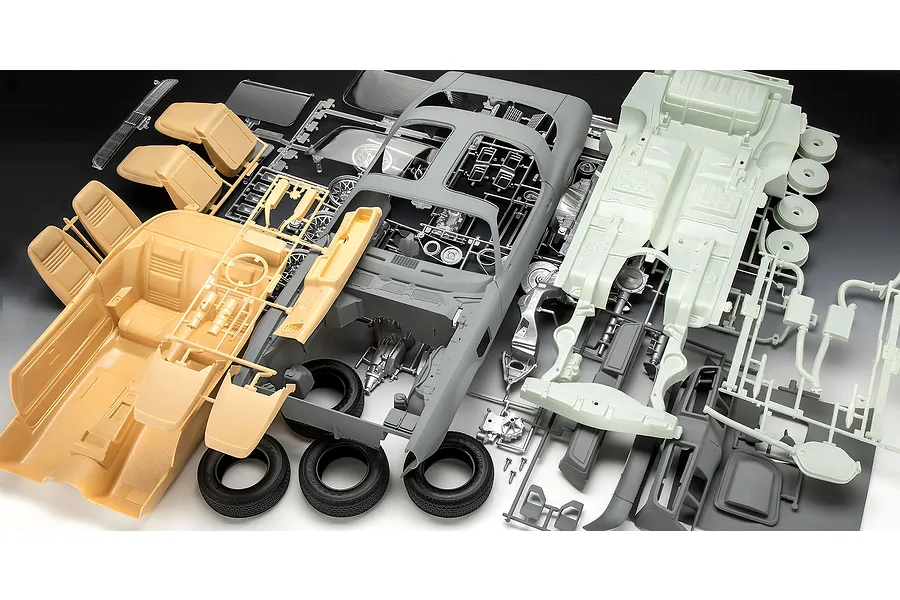 Unassembled plastic model kit parts for a Pontiac Firebird Trans Am, including car body, interior, chassis, and tires on a dark background.