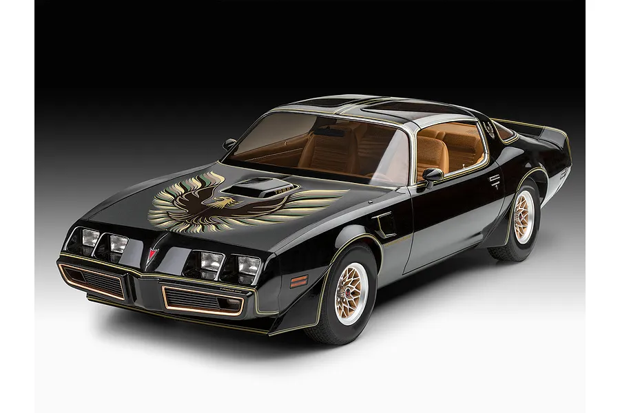 A studio shot of a black Pontiac Firebird Trans Am scale model car with a gold hood bird decal and tan interior, viewed from the front three-quarter angle.