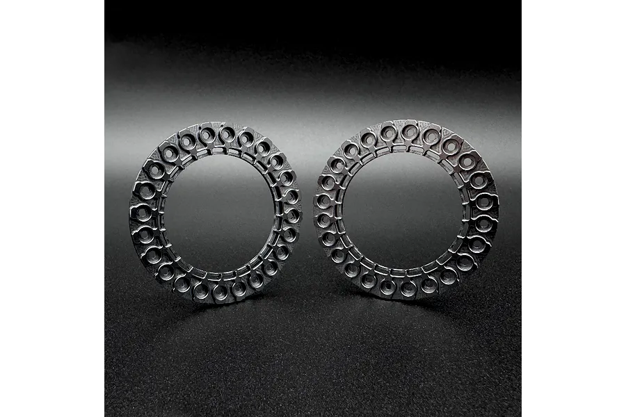 Two grey Reefs RC 1.9 inch aluminium beadlock rings standing upright on a dark surface.