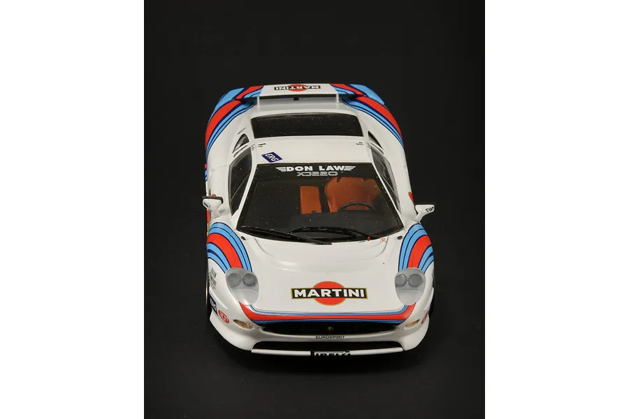 A high-angle front view of a 1/24 scale Jaguar XJ220 model car with Martini racing livery on a black background.