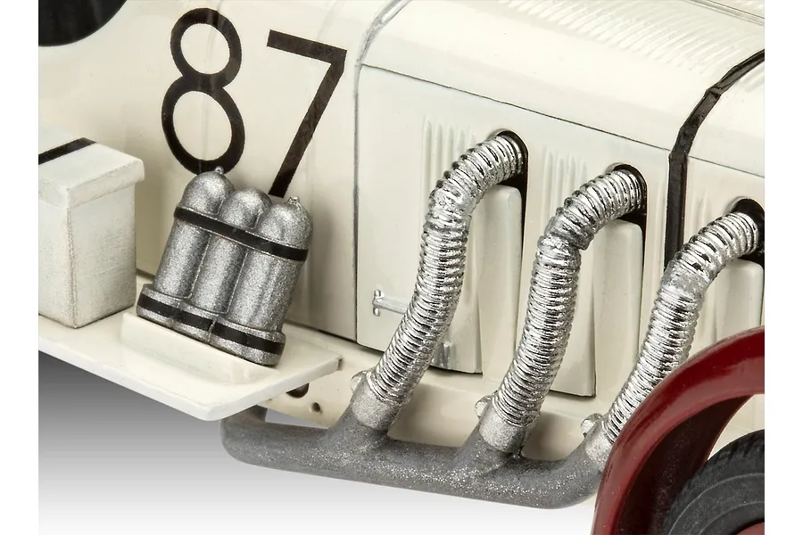 Close-up of a 1/32 scale Mercedes-Benz SSKL model car showing the side exhaust pipes, number 87 decal, and silver canisters.