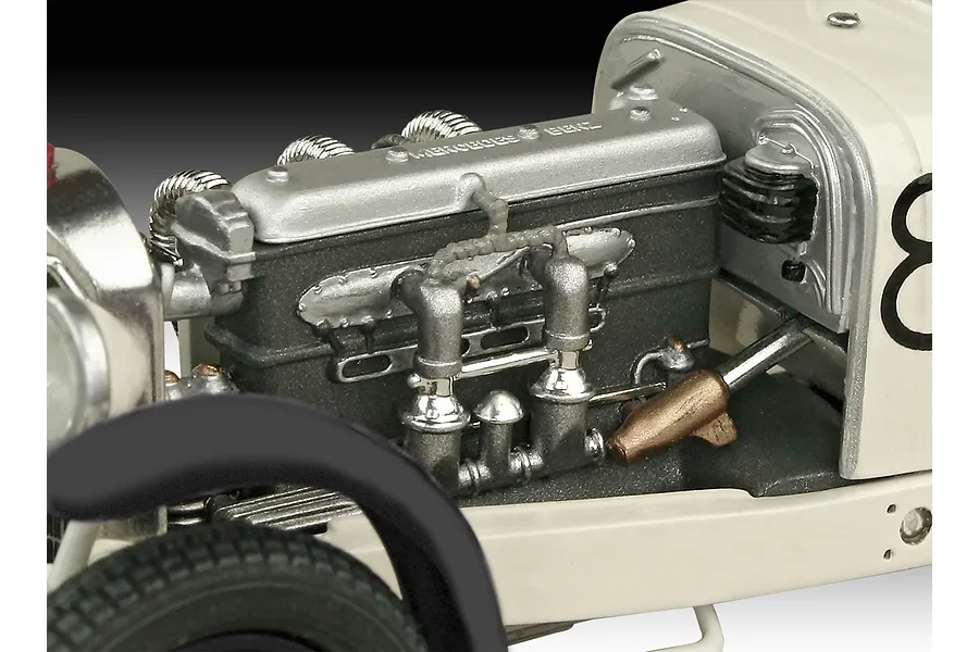 Close-up of the detailed engine bay of a 1/32 scale Mercedes-Benz SSKL model car, showing the engine block, exhaust manifolds, and chassis components.