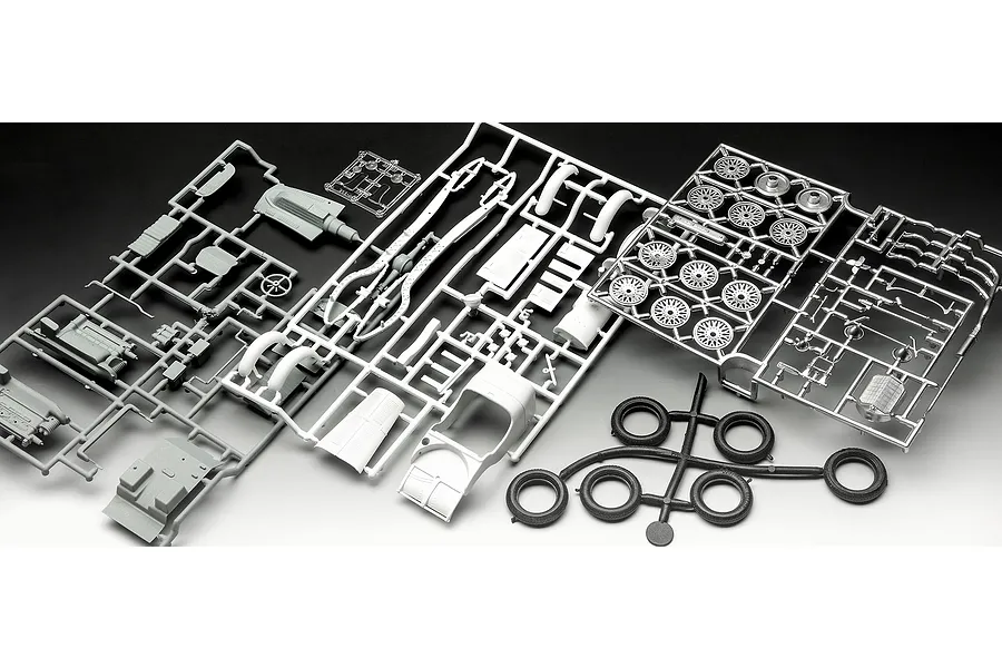 Unassembled plastic model kit parts for a Revell 1/32 Mercedes-Benz SSKL on white and black background.