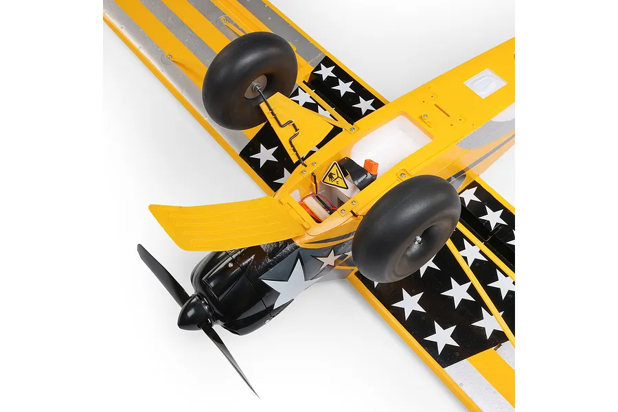 Underside view of the HobbyZone Carbon Cub S 2 RC plane showing the open battery hatch, landing gear, and star-patterned yellow and black wing design.