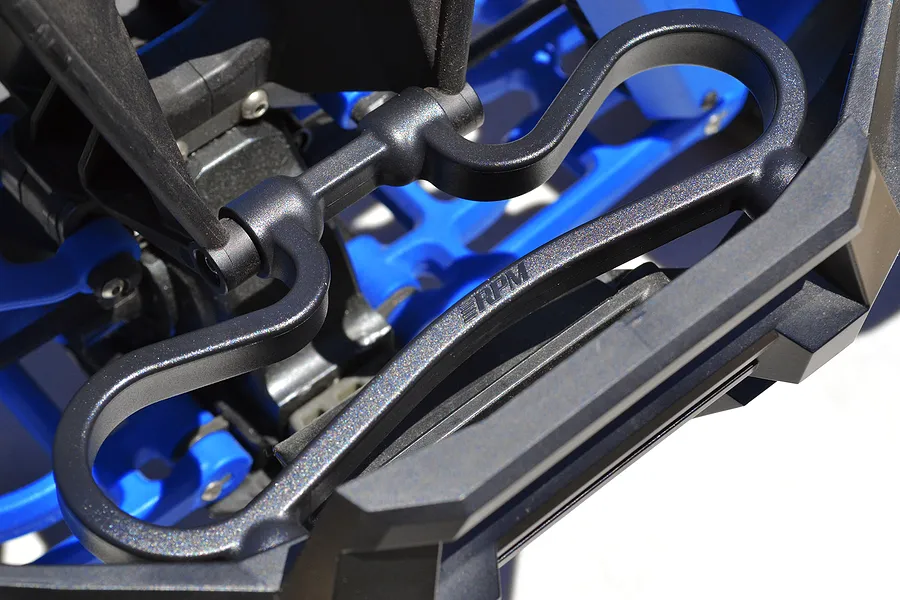 Close-up of an RPM black plastic front bumper mount installed on an RC vehicle chassis with blue suspension components.