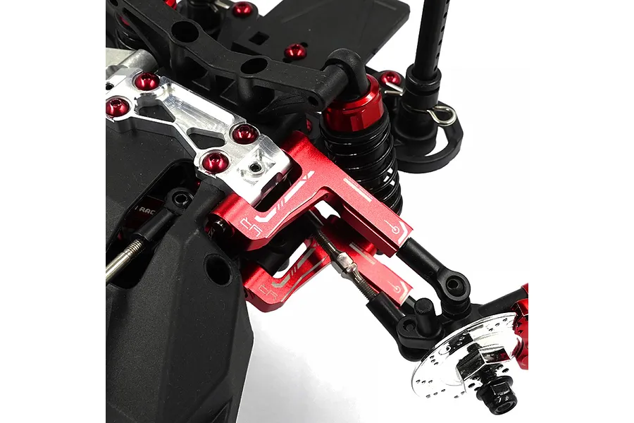 Close-up of red anodized aluminium front suspension arms installed on an RC car chassis.