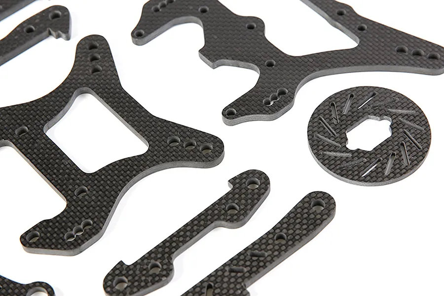 A collection of Rovan carbon fibre RC car parts including shock towers, braces, and a brake disc on a white background.
