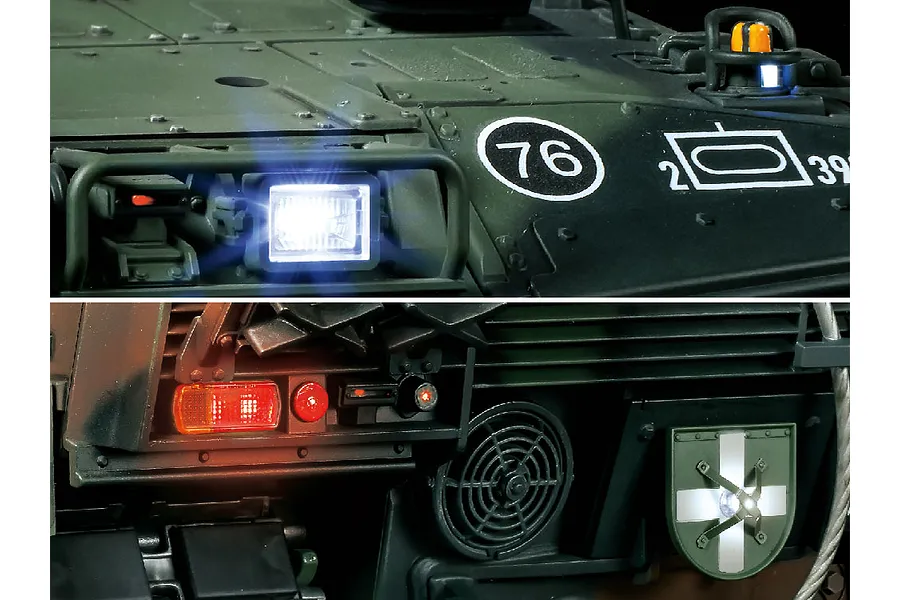 Close-up of the Tamiya Leopard 2 A7V RC tank showing illuminated front headlights and rear tail lights with tactical markings.