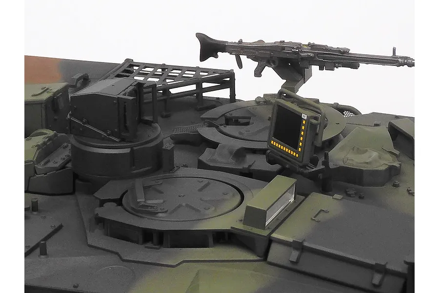 Close-up of the turret top of a Tamiya Leopard 2 A7V RC tank model, showing the machine gun, hatch, and electronic display screen.