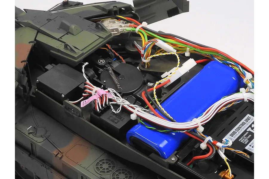 Internal view of a Tamiya Leopard 2 A7V RC tank showing the battery, wiring, and DMD control unit inside the chassis.