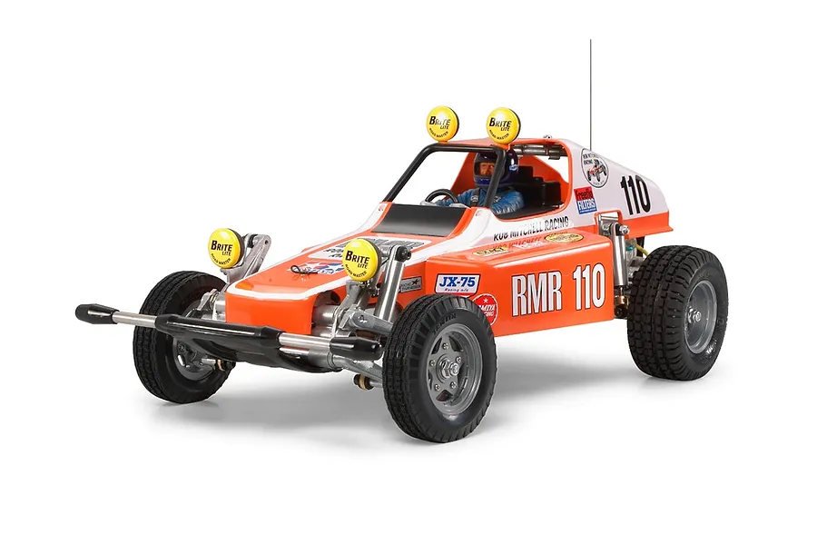 A Tamiya Racing Buggy Champ 1/10 scale RC car in orange and white with racing decals, featuring a driver figure and four yellow spotlights.