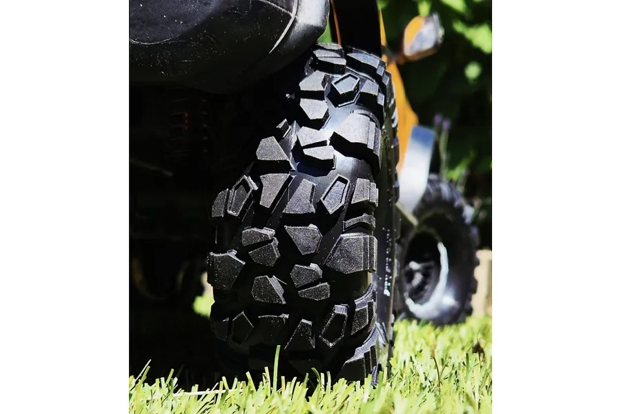 Close-up of a Louise 1.9 inch RC crawler tyre with aggressive tread pattern mounted on a black rim, positioned on green grass.