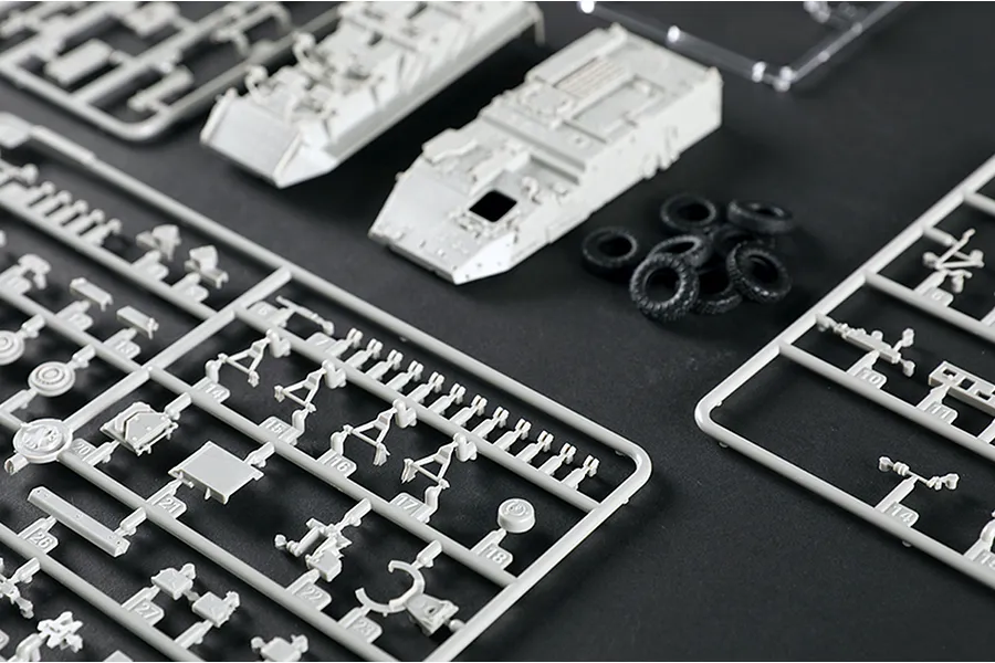Plastic model kit sprues and parts for a 1/72 scale military vehicle on a dark surface.
