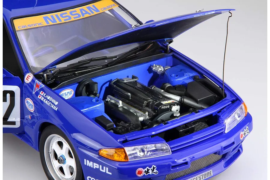 Close-up of a 1/12 scale Calsonic Nissan Skyline GT-R model car with the hood open, revealing the detailed RB26 engine bay.