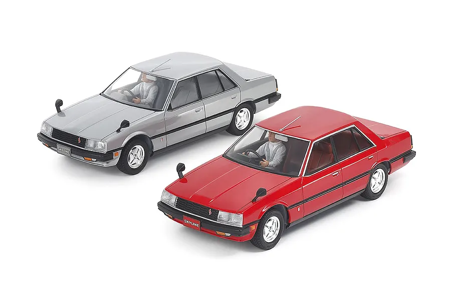 Two assembled 1/24 scale Tamiya Nissan Skyline 2000 Turbo GT-E S sedan model cars, one silver and one red, shown from a high angle on a white background.