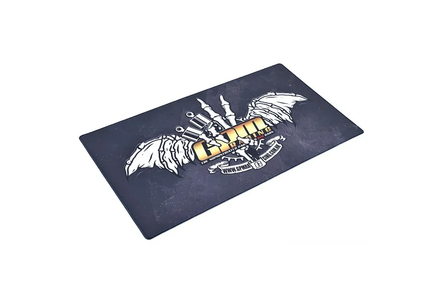 A rectangular GPM Racing pit mat featuring a dark, distressed background with a central logo of skeletal wings and gold text.