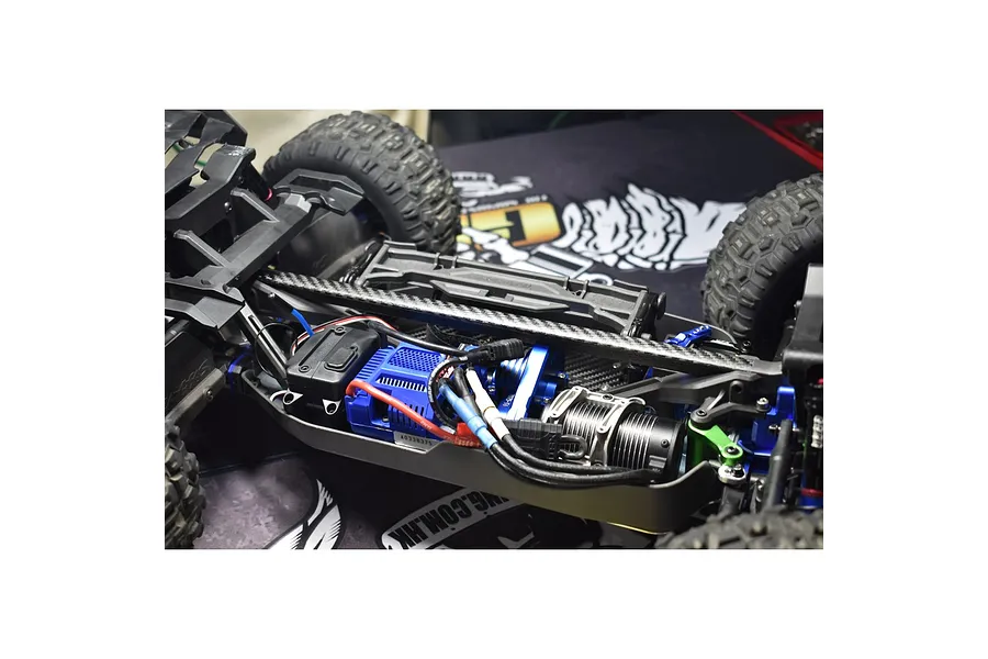 Close-up of an RC car chassis showing a carbon fibre T-bar brace installed over the central drivetrain components.